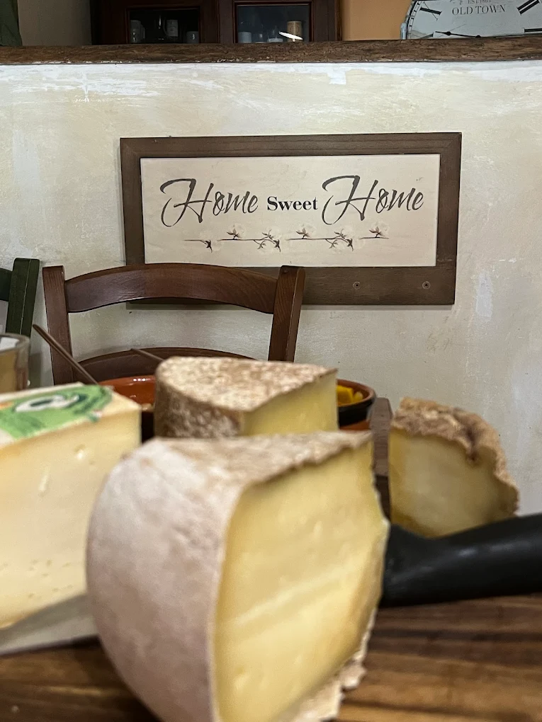 Insegna 'Home Sweet Home' appesa alla parete del locale, sopra un tagliere di formaggi